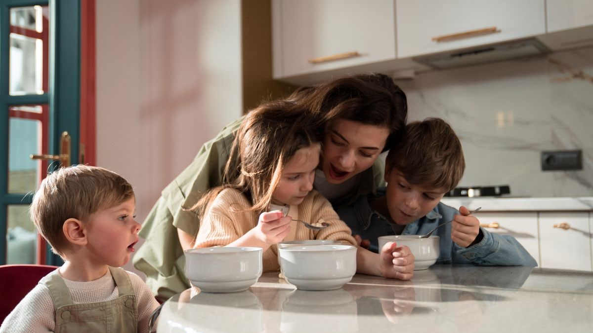 Mother and children enjoying a cozy breakfast together in a modern kitchen setting.